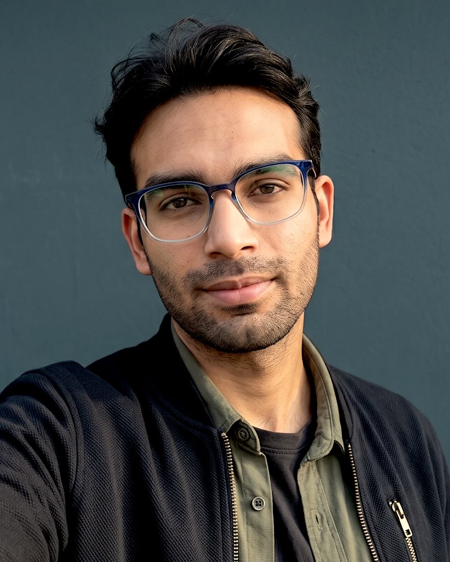 Portrait of Abhishek Kumar in glasses against a blue wall