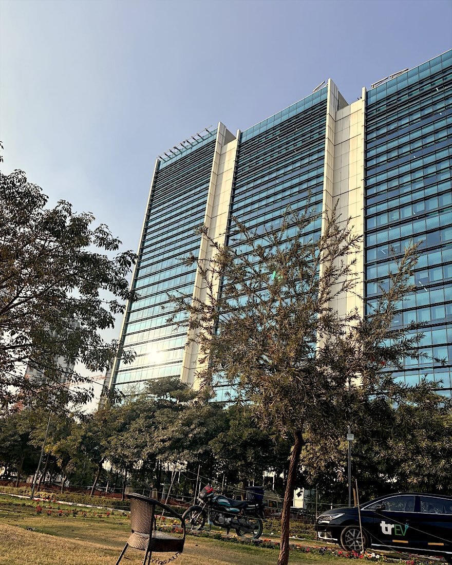 Glass office tower on a clear day, with a garden in front